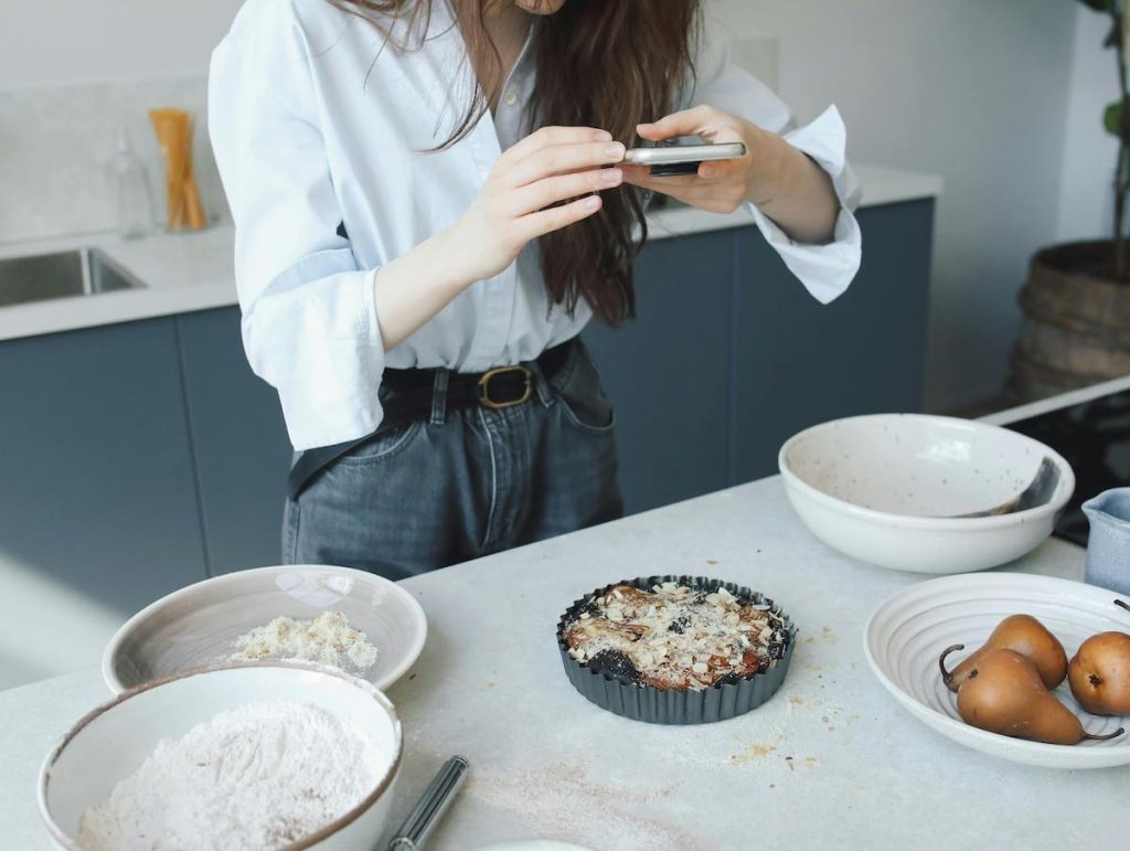 food blogger taking a photo on her phone of a pie she made