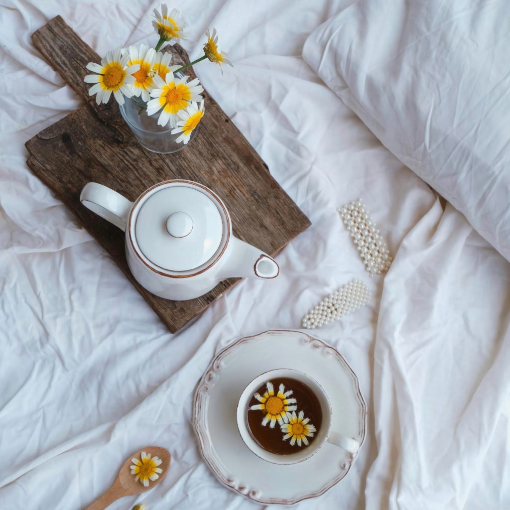 cosy tea setup in bed with daisies and pearls