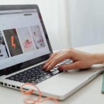 laptop with ladies hand and red fingernails